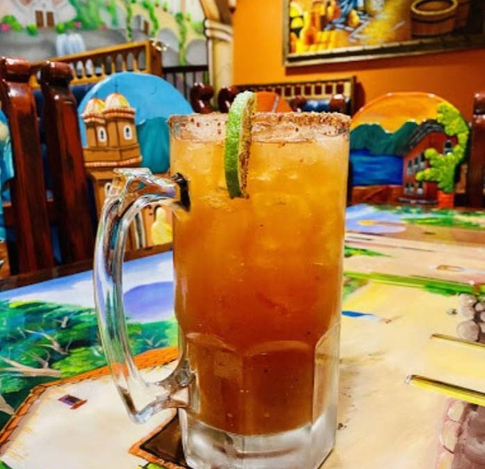 Pitcher of Mexican specialty drink with colorful Los Gallos Restaurant in the background